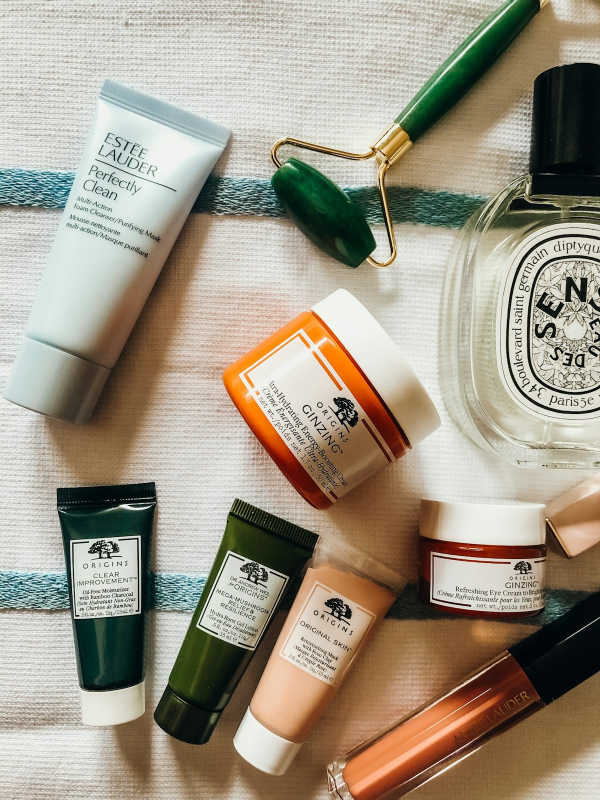 Skincare bottles and jade roller on towel